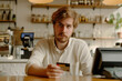 © Alina - Young man paying for order with credit card in cafe