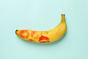 Wall Mural - Banana with red lipstick marks on turquoise background, top view. Sex concept