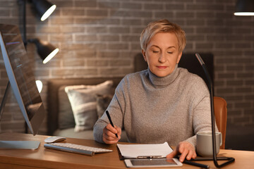 Canvas Print - Mature female programmer working in office at night