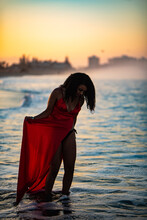 Woman Playing In  Ocean Water With Red Dress