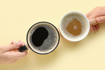 Wall Mural - Women holding cups of hot coffee on yellow background