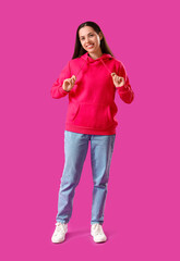 Wall Mural - Young woman in fuchsia hoodie on purple background