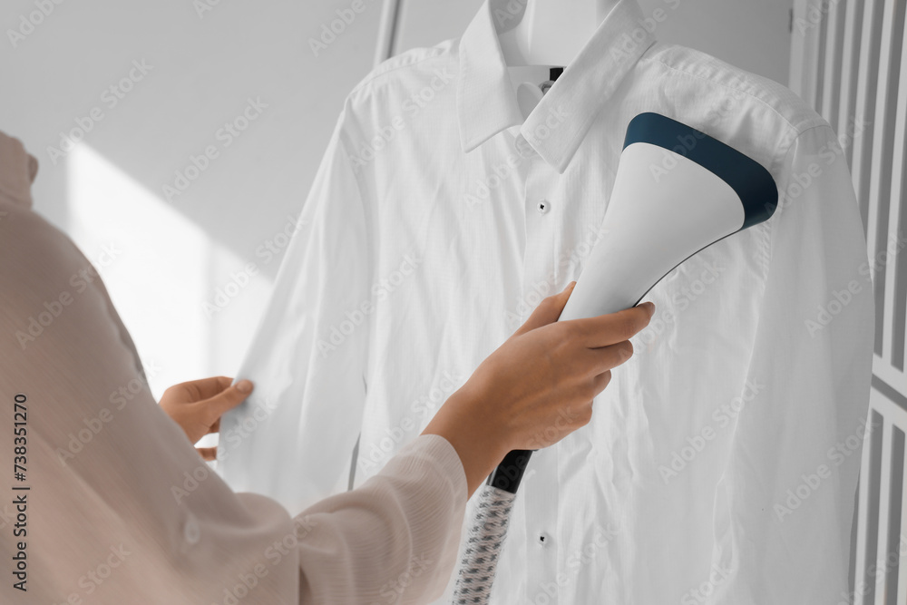 Woman steaming white shirt at home, closeup