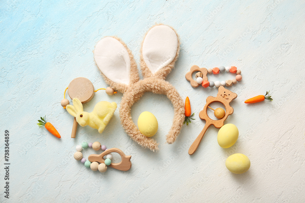 Bunny ears with Easter eggs and baby toys on light blue grunge background