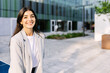 © Xavier Lorenzo - Portrait of young professional entrepreneur businesswoman smile at camera standing outside over modern company office building
