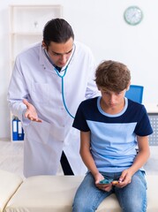 Wall Mural - Young male doctor examining boy in the clinic