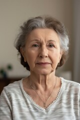 Wall Mural - Serious confident senior woman posing inside a room looking at the camera