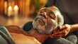© Worrapol - Elderly black man enjoying relaxing lying down with his head massaged by someone, at spa have light candle and aromatic