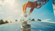 Close-up da mão de um homem com dinheiro em uma jarra de vidro e moedas em painéis solares, simbolizando o investimento em energia sustentável