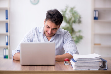 Wall Mural - Young male employee working in the office