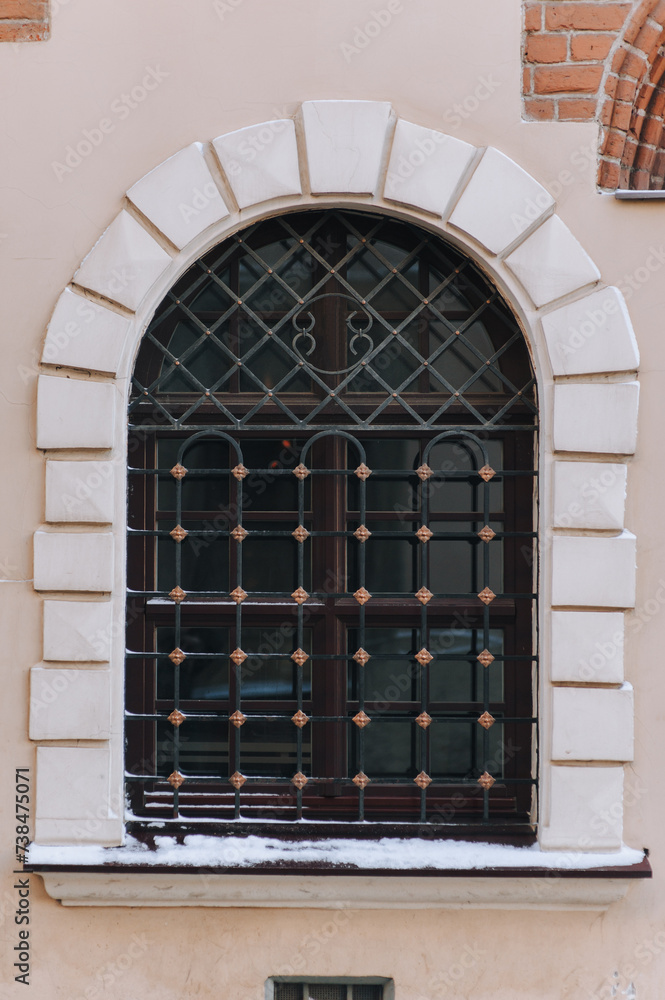 Antique semicircular old window with black iron bars in a frame on a ...