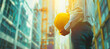 A construction worker stands proudly, holding a hardhat in hand, with a building under construction as the backdrop. This image captures the essence of construction and safety on a job site.