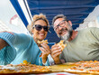© simona - Smiling couple enjoy lunch at pizzeria. Beautiful smiling couple taking selfie and having fun in pizza, having fun together. Consumerism, food, lifestyle concept