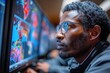 A focused African male meteorologist analyzes colorful weather patterns on multiple monitors, displaying a vibrant mix of blue and red hues.