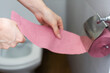 A female hand, woman holding a roll of pink toilet paper, digestive problems and defecation disorder concept.