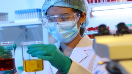 scientists are doing research in a science lab. a medical chemist in a white coat, gloves and goggle