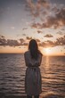 © Amit - A woman standing at a beach during sunset ai generation