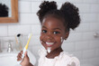 © J S - Funny dental hygiene scene of a happy black girl child smile after brushing her teeth in the morning with electric toothbrush, foam on smiling face, in bathroom with copy space on white wall tiles