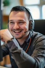 A man wearing a headset sits in front of a computer, smiling. Perfect for customer support, call centers, or remote work