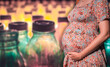 Close-up of a pregnant belly with a blurred plastic bottles on the background. Low levels of microplastics and BPA may be harmful to the normal development of babies and infants