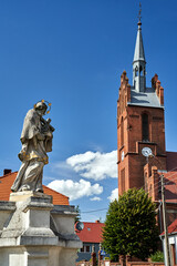 Wall Mural - Statue of Saint Nepomuk and the bell tower of the historic church in the village of Bledzew