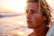 handsome young dutch or Australian blonde guy surfer closeup portrait on the beach at sunset or sunrise with his surfboard