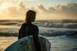 handsome young  blonde guy surfer in wetsuit  portrait on the beach at sunset or sunrise with his surfboard going in water