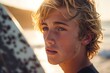 handsome young dutch or Australian blonde teenager boy surfer closeup portrait on the beach at sunset or sunrise with his surfboard
