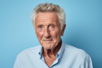 Portrait of a senior man with grey hair, isolated on blue background