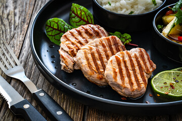 Poster - Grilled pork loin steaks with boiled white rice and mango salad on wooden table
