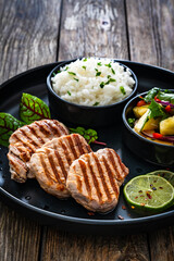 Poster - Grilled pork loin steaks with boiled white rice and mango salad on wooden table
