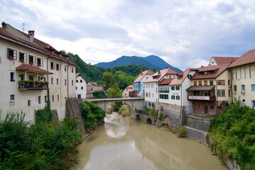 Wall Mural - Scenic view of village Skofja Loka with river and bridge on a cloudy summer day. Photo taken August 9th, 2023, Škofja Loka, Slovenia.