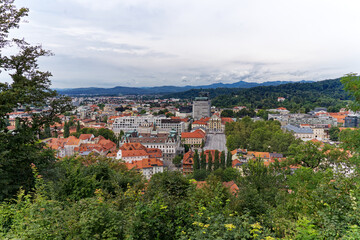 Wall Mural - Aerial view of City of Ljubljana seen from Sance castle hill with mountain panorama in the background on a cloudy summer day. Photo taken August 9th, 2023, Ljubljana, Slovenia.
