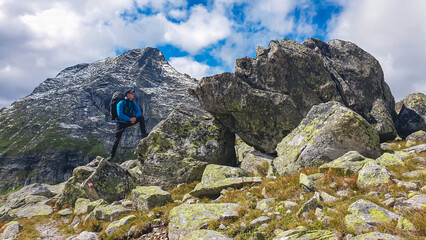 Poster - Hiker man standing in front of massive rock formation with panoramic view of majestic mountain ridge in High Tauern National Park, Carinthia, Austria. Idyllic hiking trail in Austrian Alps. Wanderlust