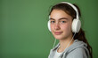zdjęcie studyjne nastoletniej dziewczyny w białych słuchawkach na zielonym tle, portret