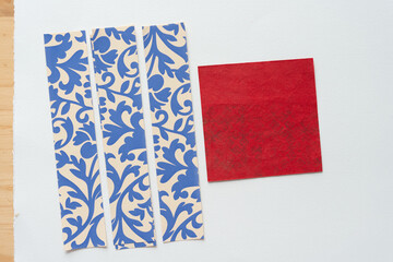 Sticker - red square with ghosting pattern and a set of paper stripes with decorative blue and tan pattern