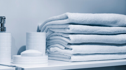 Leinwandbilder - Wash supplies and stack of towels on a shelf in a hotel, hotel service and sanitary hygiene concept background
