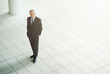 © YATrainer/peopleimages.com - Executive, portrait and smile in office building with confidence for finance of business idea. Employee, happy and professional in suit at workplace, staff and proud of company and high angle