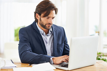Laptop, internet and report with business man at desk in office, working on corporate review or feedback. Computer, email or website with confident young employee typing information in workplace