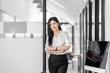 Wall Mural - Portrait of confident young Asian business woman  arms crossed smiling looking at camera in the office