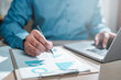 © Day Of Victory Stu. - business, finance, investment, financial, document, report, budget, account, accounting, analysis. businessman one hand typing keyboard and another use pen to calculation report and confirm to invest.