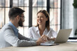 © fizkes - Friendly female bank representative with laptop communicating with male client. Smiling real estate agency adviser giving consultation to customer. Excited coworkers chatting in modern office