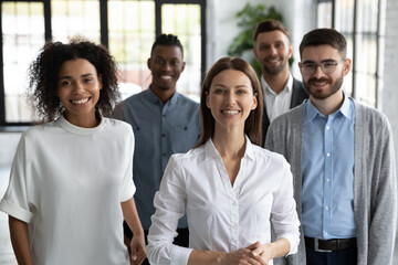 Wall Mural - Happy successful coworkers and start-up coach. Group portrait of aspiring young professionals at work, smiling and looking at camera. Friendly multiracial company staff together in modern workspace