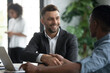© fizkes - Bank loan manager shaking hands with African client. Smiling financial advisor thanking customer for trust. Happy young entrepreneurs closing a deal. CEO welcoming new worker to modern company