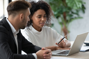 Male worker consulting female project manager or financial analyst in office. Business expert explaining possible risks to client. Young IT specialists discussing project looking at laptop screen