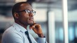 © liliyabatyrova - Close-up of a handsome young African-American businessman, boss, entrepreneur, company director, wearing glasses and a stylish suit, looking away in a modern bright office with a copy space.