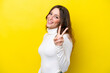 Young caucasian woman isolated on yellow background smiling and showing victory sign