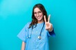 © luismolinero - Young surgeon doctor woman isolated on blue background smiling and showing victory sign