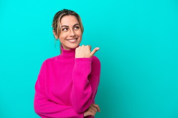 Wall Mural - Young caucasian woman isolated on blue background pointing to the side to present a product