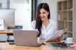 © David - Asian Businesswoman Using laptop computer and working at office with calculator document on desk, doing planning analyzing the financial report, business plan investment, finance analysis concept.